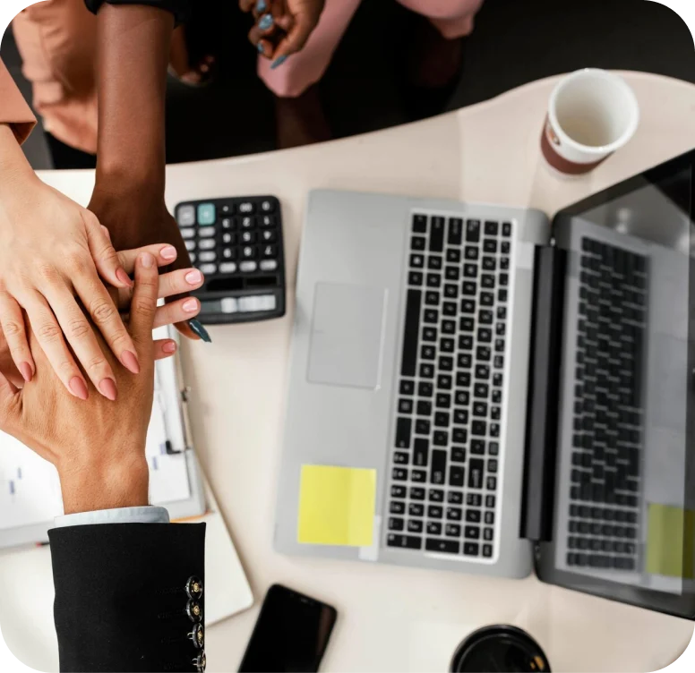 Equipo dandose la mano sobre una mesa de escritorio con ordenador