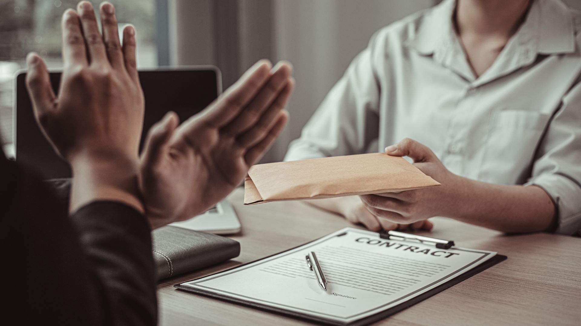 Persona ofrece un sobre a otra que le marca una cruz con las mano-antisoborno