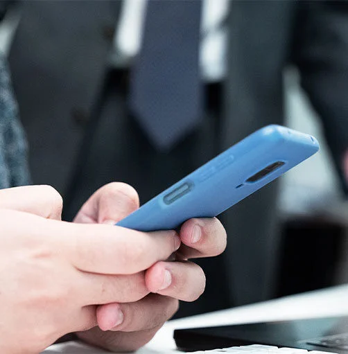 manos que cogen un movil para poner una denuncia a través del canal de denuncia